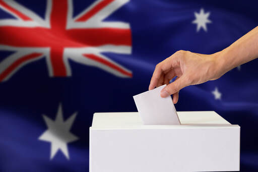A picture of someone handing off their vote with the australian flag as a background